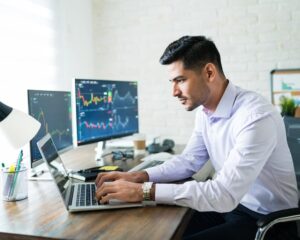 handsome-latin-freelance-broker-trading-through-laptop-desk-while-working-from-home_662251-702